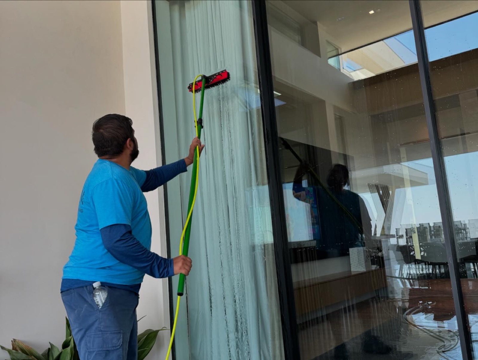 Window cleaning technician using a water-fed pole on a Las Vegas home