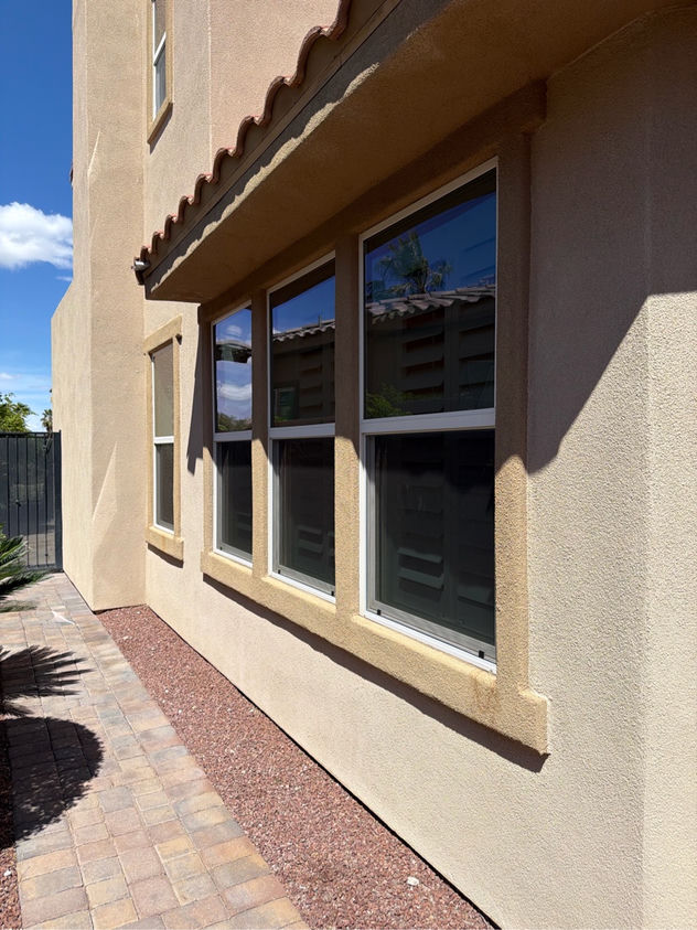 Custom window screens installed on a multi-window Las Vegas stucco home with desert landscaping and brick walkway