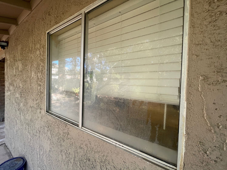 Las Vegas sliding window covered in heavy hard water mineral deposits before professional removal