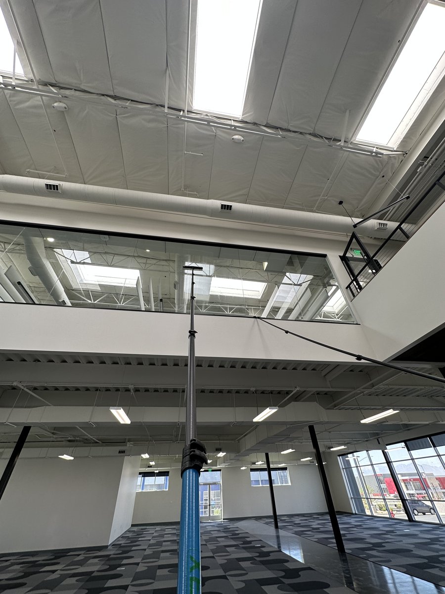 Professional window cleaning using a water-fed pole system in a multi-story commercial atrium